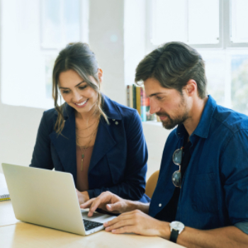 a man and woman at a table looking at a laptop
